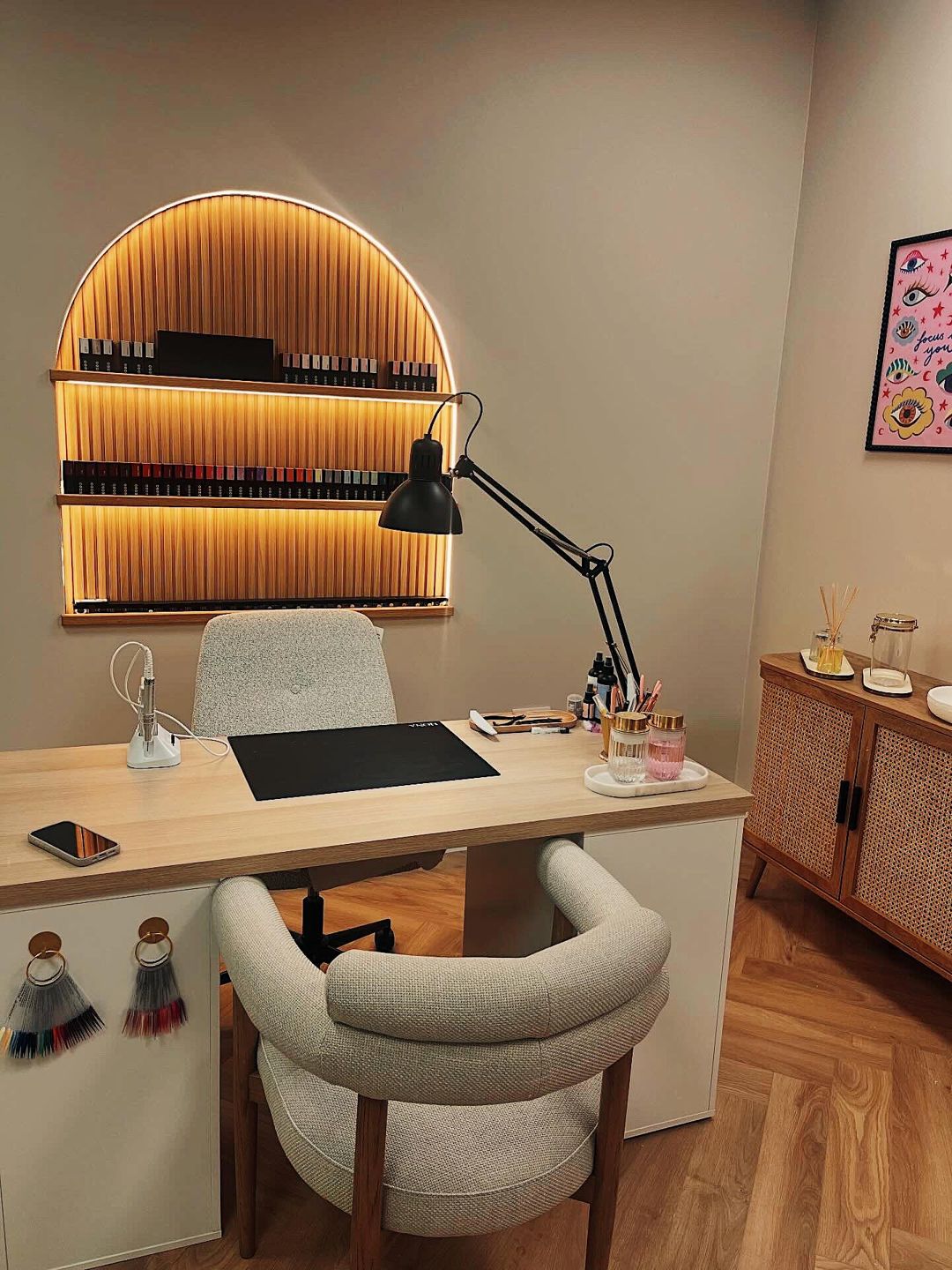 The Glossi Nails studio: nail desk, boucle chair and an arched, lit shelf of gel polishes